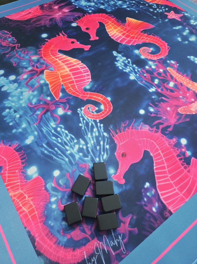 May include: A vibrant, ocean-themed game mat featuring coral, starfish, and seahorse illustrations in shades of pink and orange against a dark blue background. Several small, black rectangular game pieces are scattered on the mat. The mat has a blue border.
