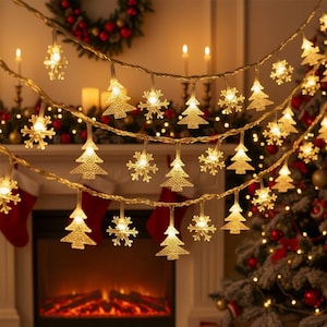 May include: A string of warm white Christmas lights with tree and snowflake shapes. The lights are strung across a fireplace and Christmas tree, creating a festive holiday scene.