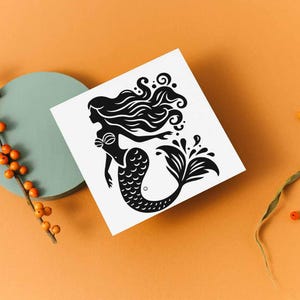 May include: A black and white mermaid illustration on a white square. The mermaid has long flowing hair and a fishtail. The image is set against an orange background with a teal circle and orange berries.