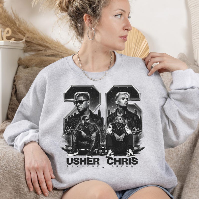 A black and white digital art piece featuring portraits of singers Usher and Chris Brown sitting in front of a stylized city skyline with the text "USHER x CHRIS" and decorative "22" branding elements.