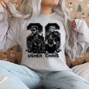 A black and white digital art piece featuring portraits of singers Usher and Chris Brown sitting in front of a stylized city skyline with the text "USHER x CHRIS" and decorative "22" branding elements.