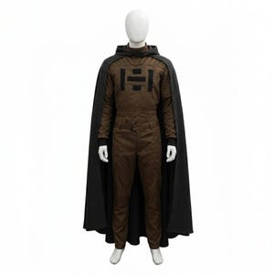 May include: A brown jumpsuit with a black graphic on the chest, a matching hood, and a long black cape. The outfit is displayed on a mannequin against a white background. The jumpsuit has long sleeves and a high collar.