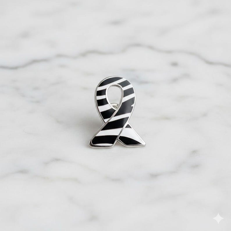 May include: A black and white striped ribbon pin with a silver border. The pin is in the shape of a ribbon, with a curved top and a loop in the middle. The stripes are evenly spaced and run horizontally across the ribbon.