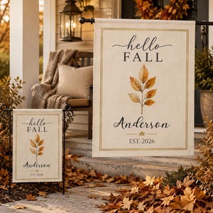 May include: Two off-white rectangular garden and house flags featuring the text hello FALL in black script and print, a central watercolor illustration of golden-brown autumn leaves, the name Anderson, and the text EST. 2026 in a thin gold border.