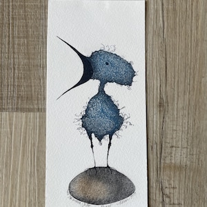 May include: A whimsical watercolor illustration of a blue creature with a large beak and textured body, standing on a brown oval. The artwork is on a white rectangular paper, with the artist's signature at the bottom.