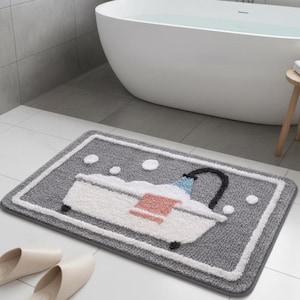 Puede incluir: Una alfombra de baño rectangular gris con un borde blanco y un diseño de bañera de dibujos animados. La bañera es blanca con una toalla rosa y un grifo negro. Burbujas blancas están esparcidas alrededor de la bañera.