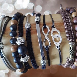 Peut inclure: Une collection de bracelets avec divers designs et matériaux. Les bracelets comprennent des perles en bois noir et marron, du macramé et des accents en métal argenté. Certains bracelets ont des symboles infinis et des perles décoratives.