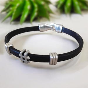 Peut inclure: Bracelet en cuir noir avec des détails en métal argenté. Le bracelet comporte un charm en forme de hashtag et une fermeture à fermoir. Un accessoire simple et élégant.