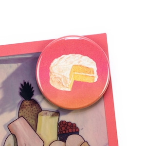 Può includere: Un bottone rotondo con uno sfondo sfumato dal rosa all'arancione. Il bottone presenta una torta bianca e gialla con una fetta rimossa.