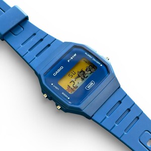 May include: A blue Casio F-91W digital watch with a matching blue strap. The watch face displays the time and day. The watch has the text "CASIO", "F-91W", "WR", "LIGHT", "MODE", and "ALARM ON/OFF".