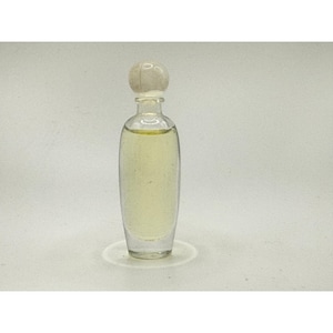 May include: A clear glass perfume bottle with a rounded, spherical stopper. The bottle has an elongated, oval-shaped body filled with a pale yellow liquid. The design is simple and transparent, showcasing the light-colored contents clearly.