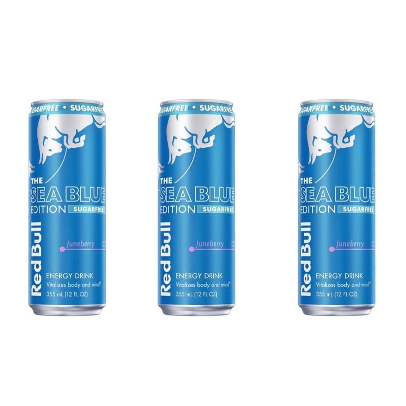 May include: Three blue Red Bull energy drink cans. The cans are labeled "The Sea Blue Edition" with "Juneberry" flavor. Each can has a white bull logo and the text "Sugarfree". Each can contains 355 ml (12 FL OZ).