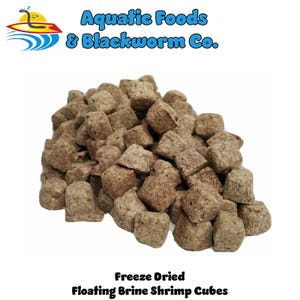 May include: A pile of freeze-dried floating brine shrimp cubes. The cubes are a light brown color and have a rough, textured appearance. The text "Aquatic Foods & Blackworm Co." and "Freeze Dried Floating Brine Shrimp Cubes" are visible.