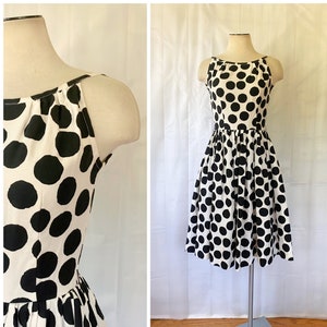 May include: A white sleeveless dress with a black polka dot pattern. The dress has a fitted bodice and a full skirt.