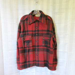 Peut inclure: Une chemise en flanelle à carreaux rouge et noir à manches longues et deux poches à rabat. La chemise a une fermeture boutonnée à l'avant et un col.