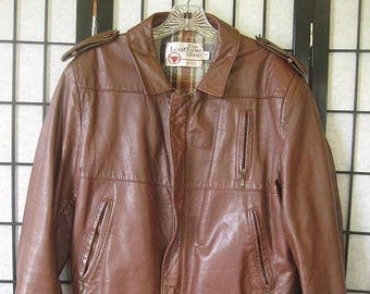 May include: A brown leather jacket featuring a collared neckline, shoulder epaulets, and a front zipper closure. The jacket includes two vertical zippered chest pockets, two lower zippered pockets, and a dark brown ribbed knit hem and cuffs.