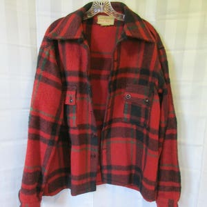May include: Red, black, and green plaid flannel shirt with a button-up front and two flap pockets. The shirt has a "Milt-Dell" label.