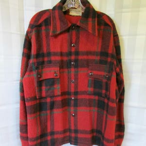 May include: Red, black, and green plaid flannel shirt with a button-up front and two flap pockets. The shirt has a "WOLF-DELL" label.