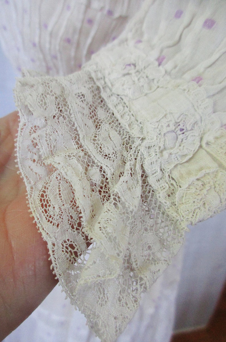 May include: Close-up of a white lace trim with a delicate floral pattern. The lace is ruffled and has a soft, vintage look.