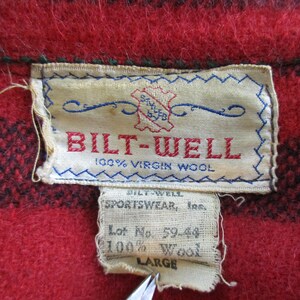 May include: A red and black plaid wool shirt with a white label that reads "BILT-WELL 100% VIRGIN WOOL". The label also includes the text "SPORTSWEAR, Inc. Lot No. 59-44 100% Wool LARGE".