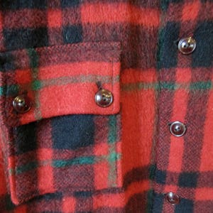 May include: Red, black, and green plaid flannel shirt with a patch pocket and dark brown buttons.