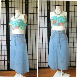 Peut inclure: Ensemble vintage deux pièces sur mannequin. Le haut est un bustier à imprimé floral avec des fleurs roses, bleues et vertes. La jupe en jean taille haute est bleu clair avec des poches zippées marron. Un collier assorti complète le look.