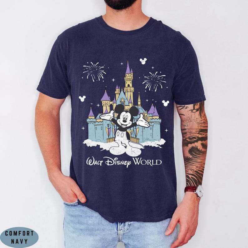 Op de afbeelding: Marineblauw T-shirt met een afbeelding van Mickey Mouse voor het kasteel van Assepoester in Walt Disney World. Het ontwerp bevat vuurwerk en de tekst "Walt Disney World".