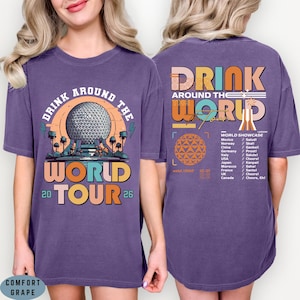May include: Purple t-shirt with a graphic design featuring the text "DRINK AROUND THE WORLD TOUR 2026". The front design includes a sphere and the back design includes a list of countries and phrases.