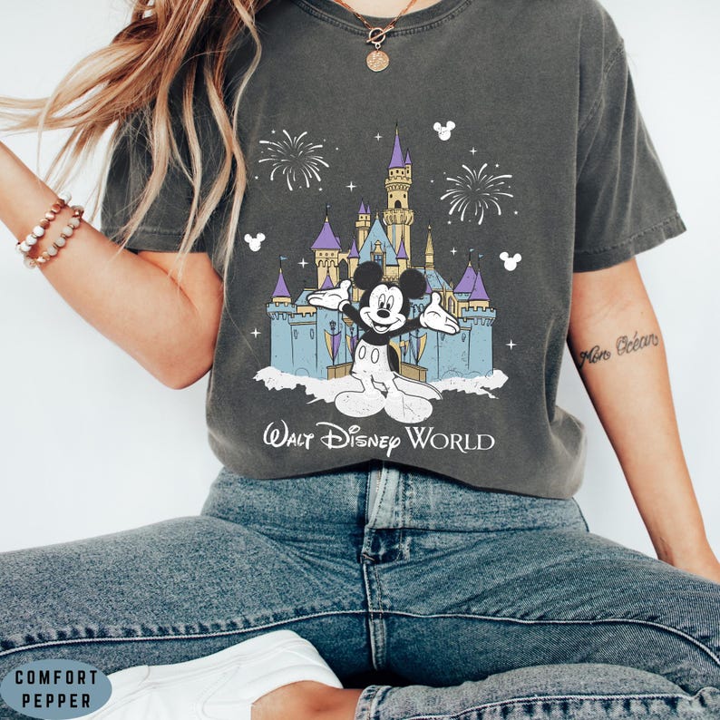 Op de afbeelding: Donkergrijs T-shirt met een afbeelding van Mickey Mouse voor het kasteel van Assepoester in Walt Disney World. Het ontwerp bevat vuurwerk en de tekst "Walt Disney World". Het shirt heeft een relaxte pasvorm.