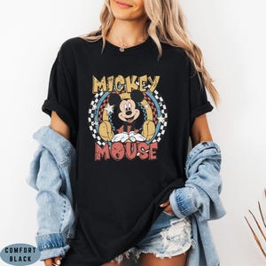 Puede incluir: Una camiseta negra de manga corta con un gr&aacute;fico de Mickey Mouse centrado en un dise&ntilde;o circular. El gr&aacute;fico incluye el texto MICKEY MOUSE en letras negritas, rodeado por un patr&oacute;n de cuadros, estrellas y detalles en amarillo y azul.