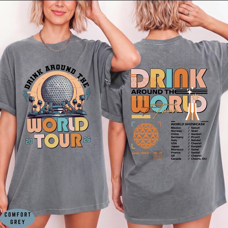 May include: Comfort grey t-shirt with a graphic design. The front features the text "DRINK AROUND THE WORLD TOUR 26" with a colorful illustration. The back of the shirt has "DRINK AROUND THE WORLD" and a list of countries.