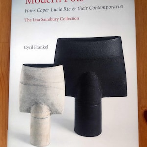 May include: A book cover titled "Modern Pots" featuring two ceramic sculptures. The book's title is in red, with the subtitle mentioning Hans Coper and Lucie Rie. The sculptures are a white and black form.