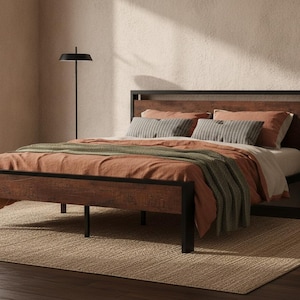 May include: A bed frame featuring a black metal structure and dark wood grain panels on the headboard and footboard. The bed is dressed with a solid rust-colored duvet, a folded olive green textured throw blanket, and two striped gray pillows.