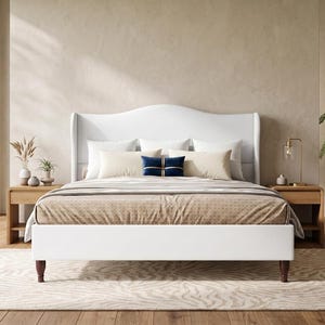 May include: A white upholstered bed frame with a curved wingback headboard and dark wooden legs. The bed is dressed with a tan patterned coverlet, two white pillows, two beige rectangular pillows, and a small navy blue decorative pillow.