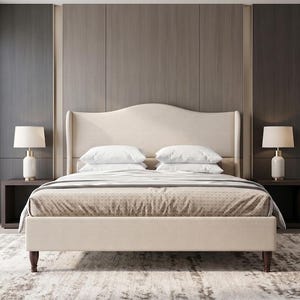May include: A beige upholstered bed frame with a curved, high-back headboard and dark wooden legs. The bed is dressed with a patterned beige coverlet and two white pillows. Two white table lamps with cylindrical bases sit on dark side tables.
