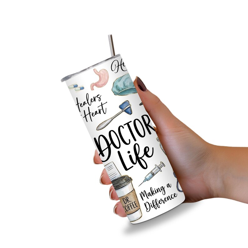 May include: A white tumbler with a silver straw, held in a hand. The tumbler is decorated with medical-themed illustrations, including a stomach, pills, and a reflex hammer. The words "DOCTOR LIFE" are prominently displayed, along with "Healers Heart" and "Making a Difference."