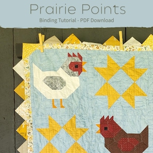May include: A light blue quilt with a chicken and star pattern. The quilt has a yellow and white patterned border and the text "Prairie Points Binding Tutorial - PDF Download".