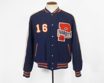 May include: A navy blue varsity jacket with white and orange stripes. The jacket has a large "P" with "Varsity '79" embroidered on the right side of the chest. The number "16" is on the left side of the chest.
