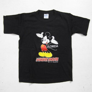 May include: Black short-sleeved t-shirt featuring a cartoon image of Mickey Mouse with the text "Florida" and "Mickey Mouse" printed on the front.
