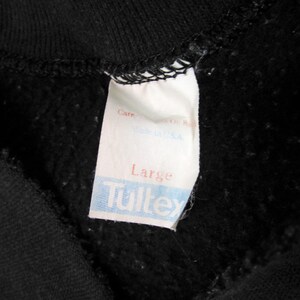 May include: A white tag with black text that reads "Care", "Made in U.S.A.", "Large", and "Tultex".