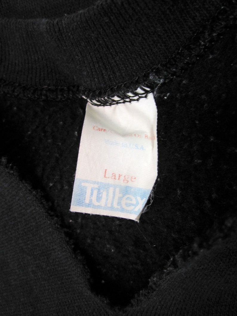 May include: A white tag with black text that reads "Care", "Made in U.S.A.", "Large", and "Tultex".