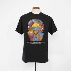 May include: Black t-shirt featuring a colourful graphic of a Native American face and the text "SANTA FE INDIAN MARKET 1999 Southwestern Association for Indian Arts".