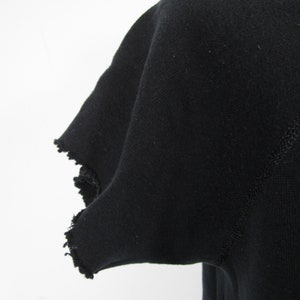 May include: Black t-shirt with a frayed edge on the sleeve.