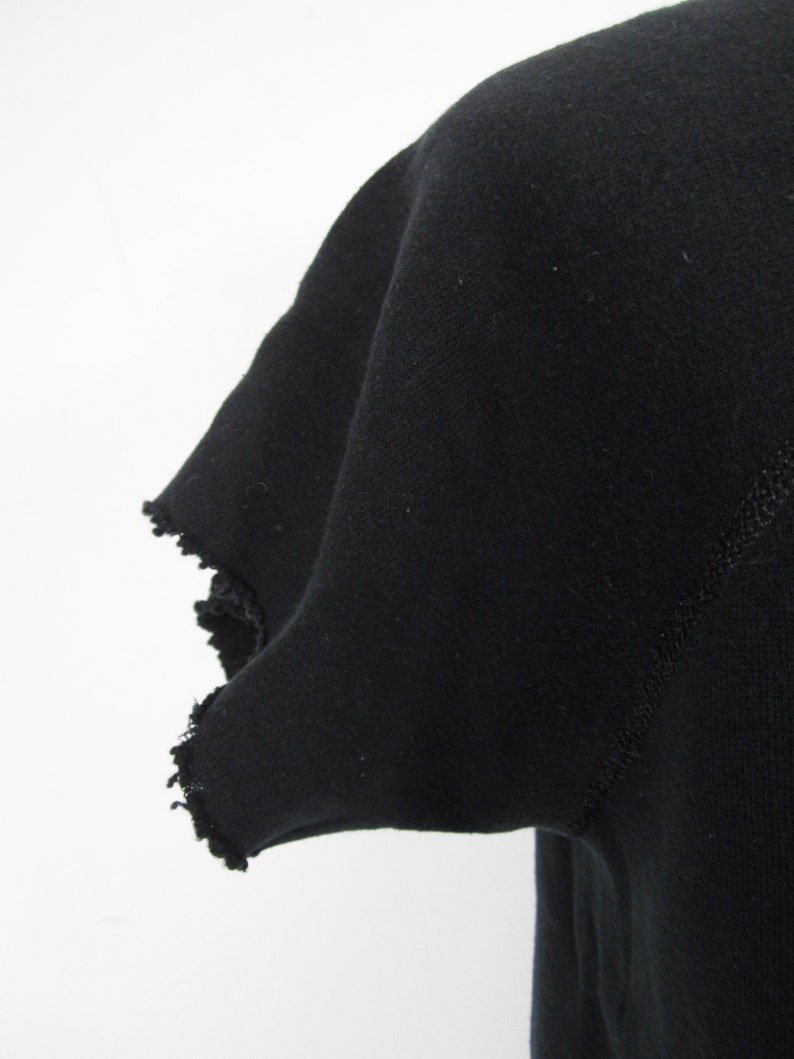 May include: Black t-shirt with a frayed edge on the sleeve.
