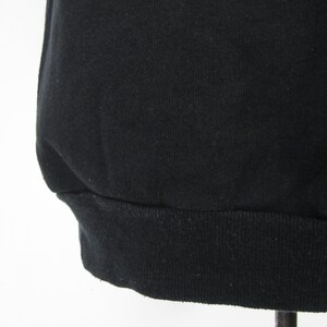 May include: Black sweatshirt with a ribbed hem.