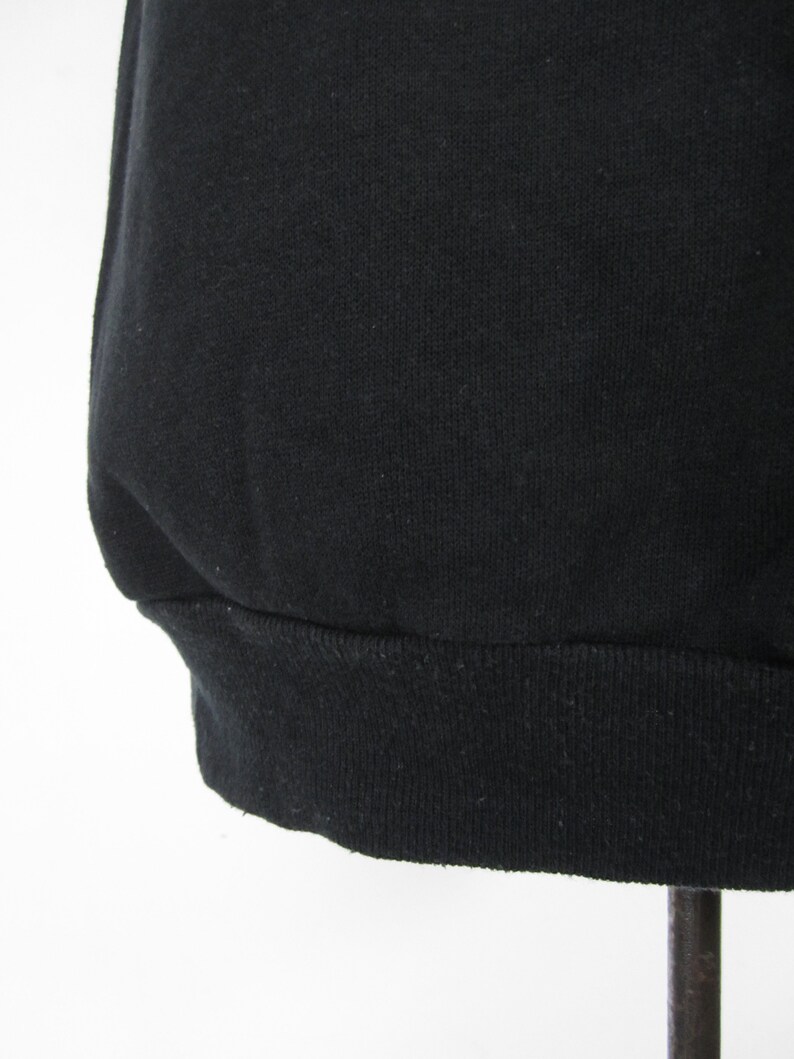May include: Black sweatshirt with a ribbed hem.