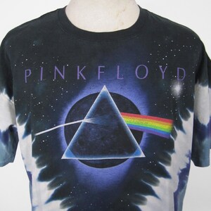 K&ouml;nnte beinhalten: Schwarzes T-Shirt mit Batikmuster und dem Pink Floyd Albumcover. Das Design zeigt ein schwarzes Dreieck, einen Regenbogen und den Namen der Band in lila Schrift. Das T-Shirt hat einen Rundhalsausschnitt und kurze &Auml;rmel.