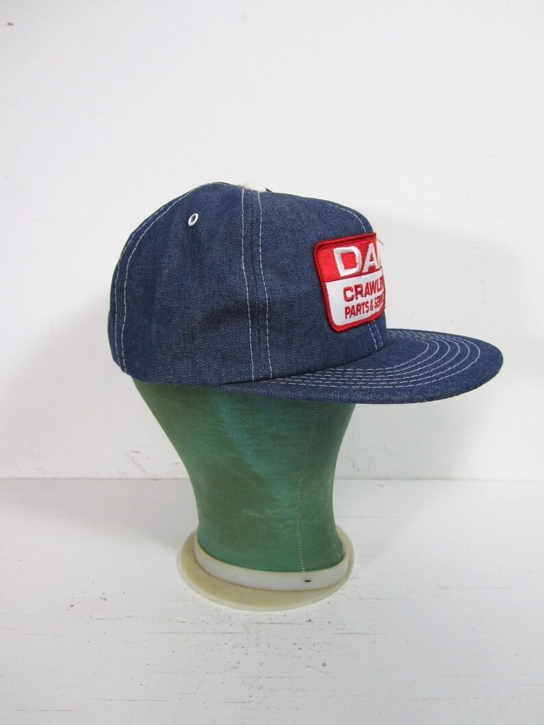 Puede incluir: Una gorra de b&eacute;isbol de mezclilla azul con una visera cosida blanca y un parche rojo y blanco que dice "DANA CRAWLER PARTS & SERVICE".