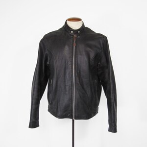 Puede incluir: Chaqueta de cuero negro con cuello alzado y cremallera completa. La chaqueta tiene un diseño clásico con un corte entallado, costuras visibles y un tirador de cremallera marrón. La chaqueta se exhibe en un maniquí sobre un fondo blanco.