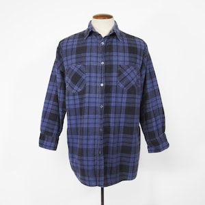 Puede incluir: Una camisa de franela a cuadros azules y negros con mangas largas y cierre de botones.